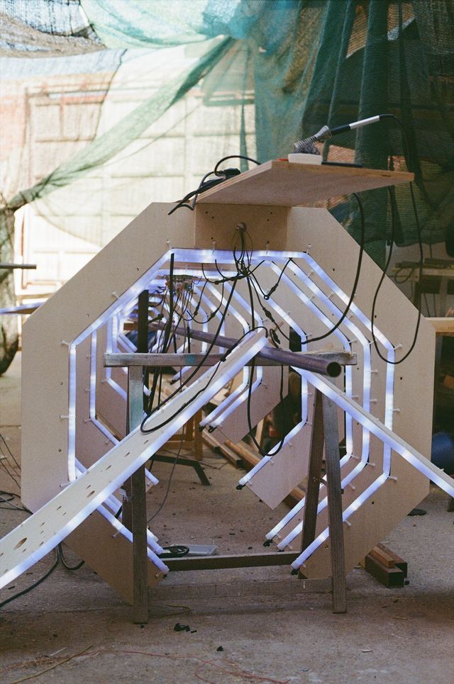A film photograph looking through the whale's ribs during a lighting test, with white LED tubes and their wiring visible.