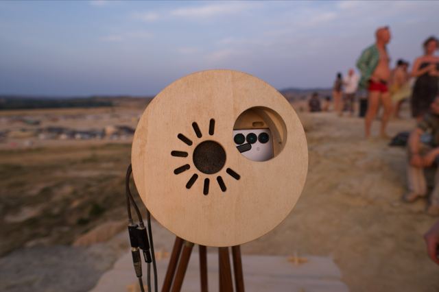 The wooden front of the telescope has a sun motif and a round opening for the phone's camera.