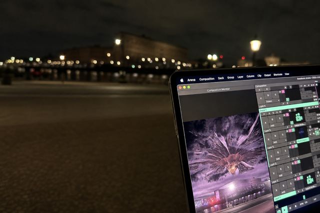 A laptop running the alien invasion scene in Resolume overlooks the softly lit Stockholm waterfront at night.