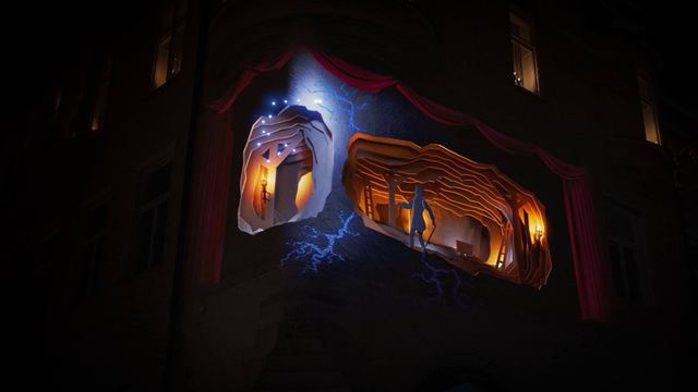 An illuminated face and warm architectural forms are projected across a curved building facade at night.