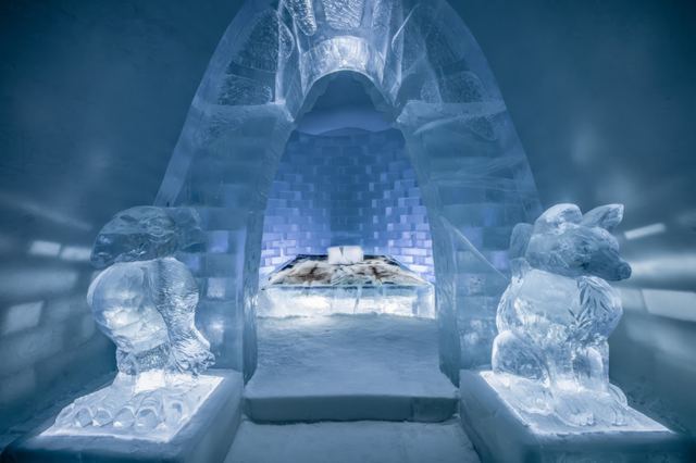 An ice bed sits within a tall carved alcove, flanked by ice sculptures and lit in pale blue.