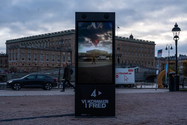 A freestanding screen stands in front of the Royal Castle, showing an altered view of the square.