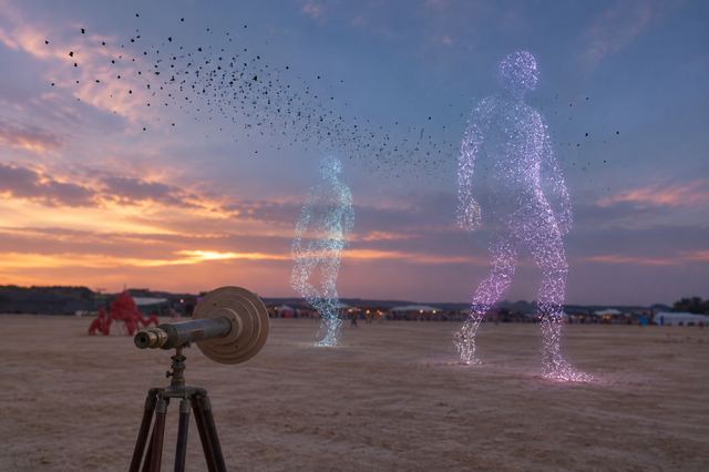 Concept image of the telescope at sunset, with two towering cyan and violet particle figures walking on the open sand in front of the camp and a flock of virtual birds crossing the sky.
