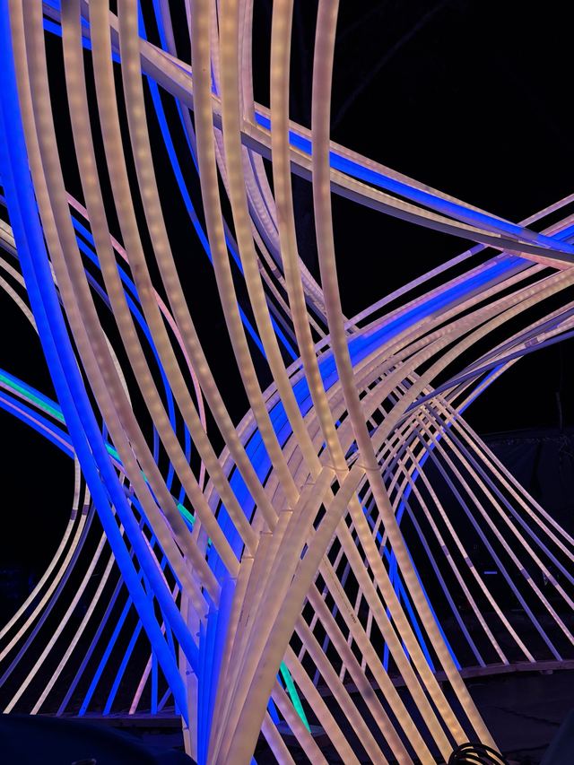 A close view of blue and warm-white ribs shows the LED strips inside the translucent tubes as they bend and overlap.