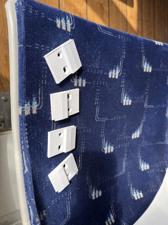 White 3D-printed mounting saddles lie on blue fabric before installation.