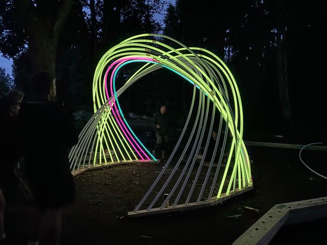 An early section of Kagora glows green, pink and blue as its curved ribs are tested outdoors.